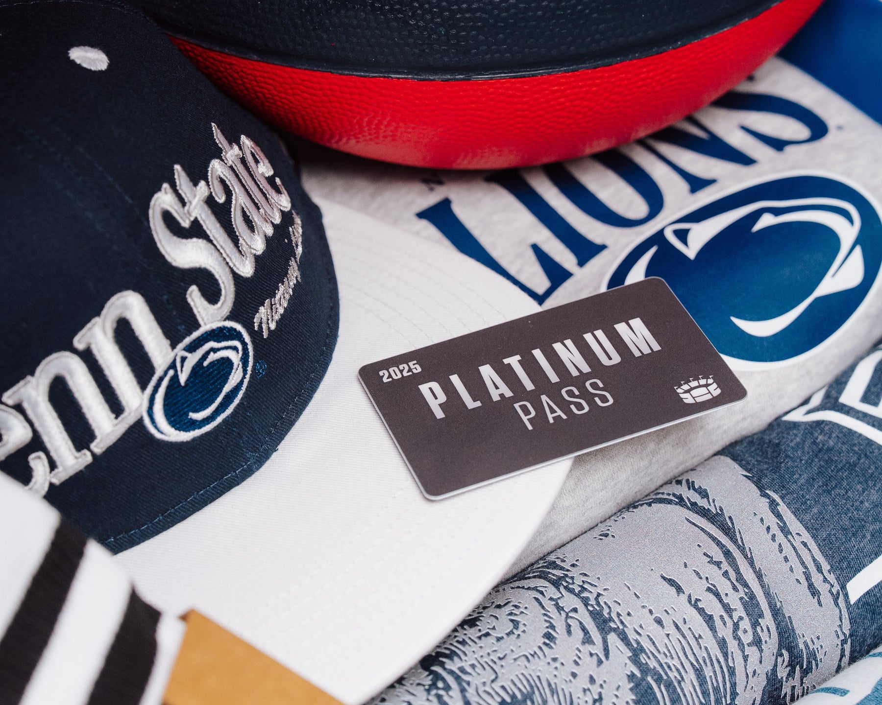 Homefield branded sports ball with Penn State cap, Lions jersey, and platinum pass on a patterned surface.